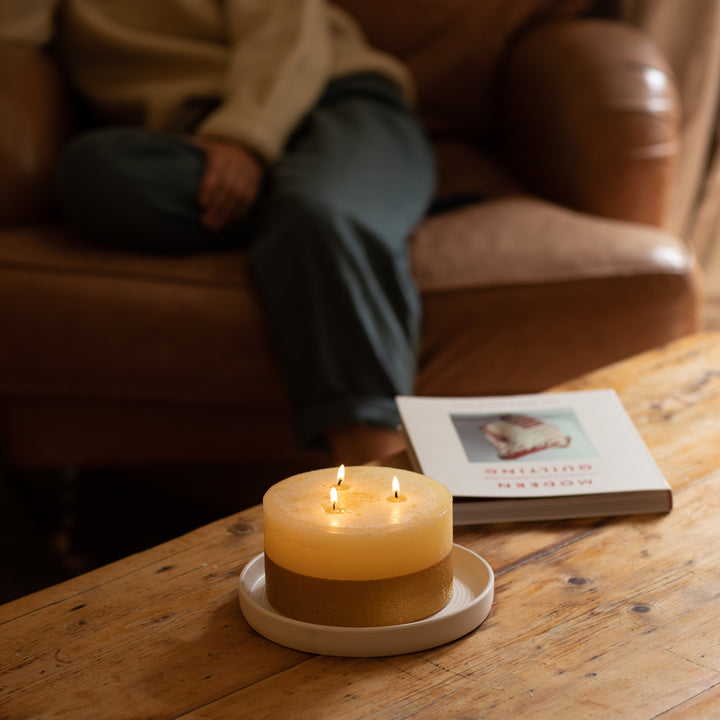 Softly lit Inspiritus Scented Gold Dipped Multiwick and Pillar Candles on a green ceramic plate
